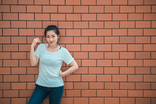 Retrato de uma linda garota chique asiática posar para tirar uma foto na parede de tijolosEstilo de vida do povo adolescente da TailândiaConceito feliz de mulher moderna