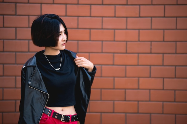 Retrato de uma linda garota chique asiática posar para tirar uma foto no fundo da paredeEstilo de vida do povo adolescente da Tailândia Conceito feliz de mulher modernaEstilo punk rock