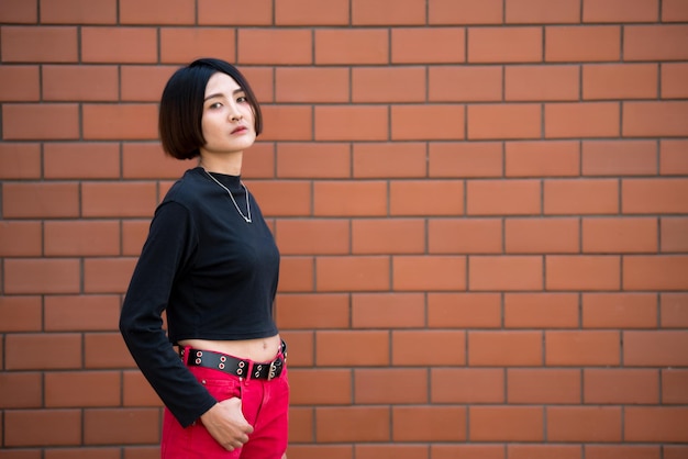 Retrato de uma linda garota chique asiática posar para tirar uma foto no fundo da paredeEstilo de vida do povo adolescente da Tailândia Conceito feliz de mulher modernaEstilo punk rock