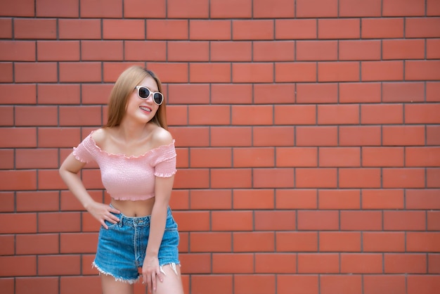 Retrato de uma linda garota chique asiática vestindo pose de vestido preto para tirar uma foto na parede de tijolosEstilo de vida do povo adolescente da Tailândia Conceito feliz de mulher modernaEstilo da Coreia