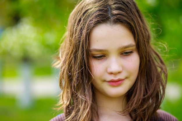 Retrato de uma linda garota com cabelo loiro escuro em um parque da cidade na primavera