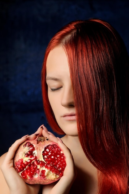 Retrato de uma linda garota com cabelo vermelho e frutas de romã no fundo de diferentes poses de parede azul