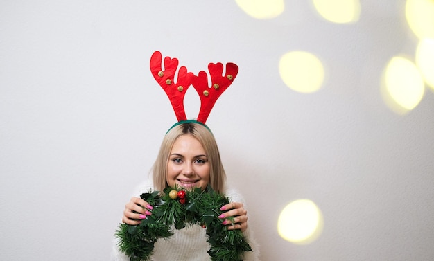 Retrato de uma linda garota com chifres de veado em um fundo branco com bokeh ConceptNatal