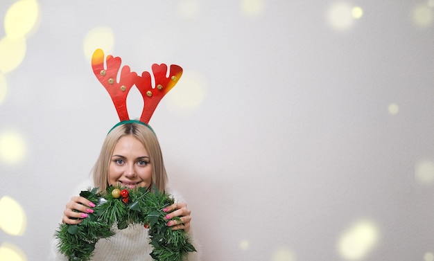 Retrato de uma linda garota com chifres de veado em um fundo branco com conceito bokeh Natal novo