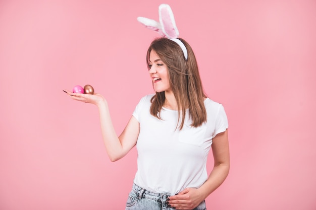 Retrato de uma linda garota com orelhas de coelho em pé isolado sobre o rosa