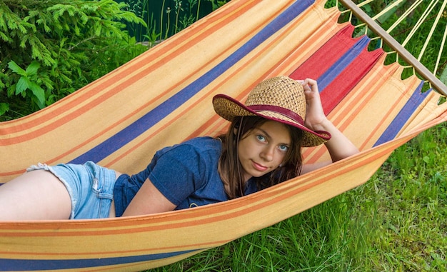 Retrato de uma linda garota com um chapéu de palha deitado em uma rede