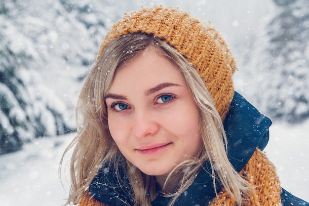 Retrato de uma linda garota com um chapéu em um fundo de paisagem de inverno