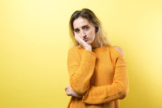 Retrato de uma linda garota com um suéter laranja olhando de lado com expressão pensativa