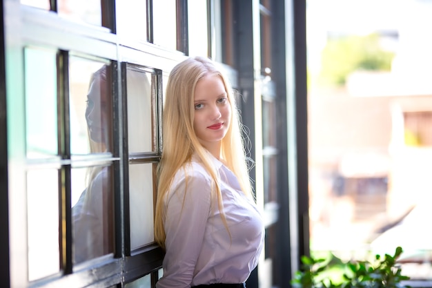 retrato de uma linda garota da moda com cabelo loiro posado em ambiente interno