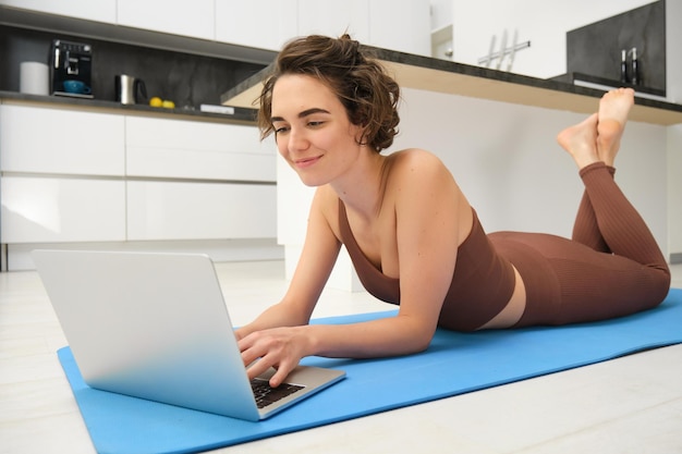 Retrato de uma linda garota desportista assistindo a vídeos no laptop durante o treino siga online