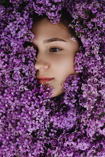 Retrato de uma linda garota em flores lilás no jardim primavera