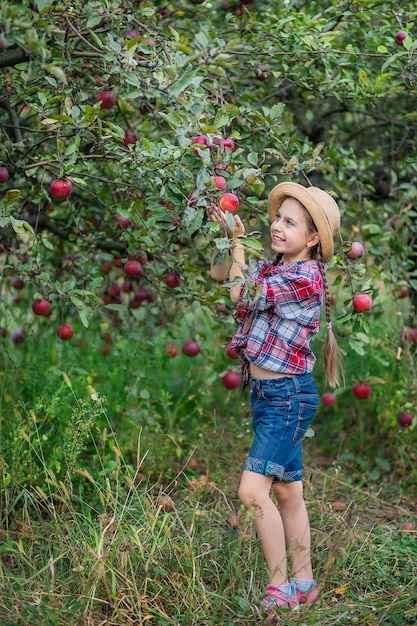 Retrato de uma linda garota em um jardim de fazenda com uma maçã vermelha Colheita de maçãs no outono