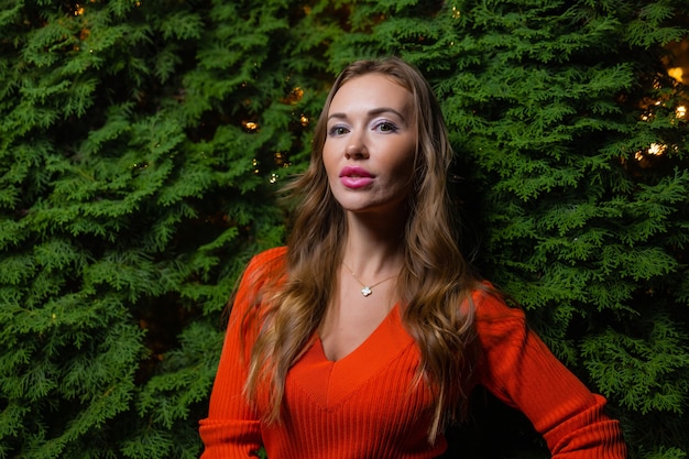 Retrato de uma linda garota em um vestido vermelho cor de vinho em um fundo de folhas de videira no parque