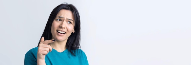 Retrato de uma linda garota em uma camiseta azul olha de lado com expressão pensativa está considerando um plano para ação adicional