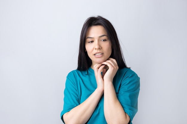 Retrato de uma linda garota em uma camiseta azul, olhando para o lado com expressão pensativa, está considerando um plano de ação.