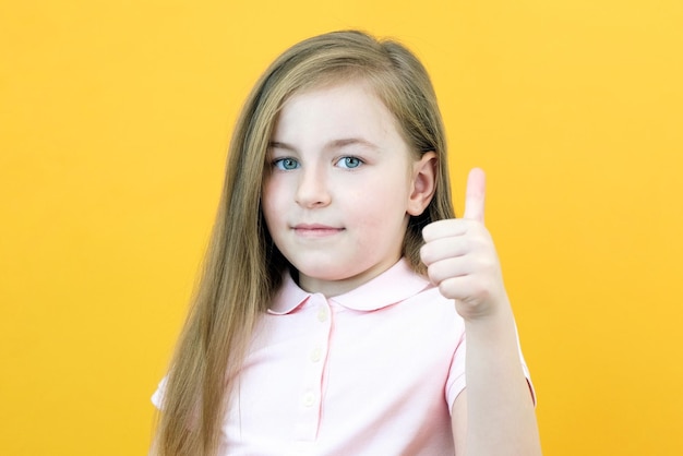 Retrato de uma linda garota espantada apontando para um espaço vazio no fundo, uma garota pré-escolar mostra um gosto em um fundo amarelo