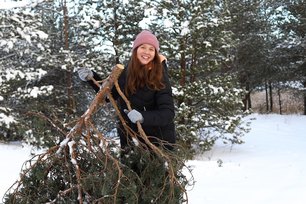 Retrato de uma linda garota fofa recebendo uma árvore de Natal na floresta mulher se divertindo rindo sorrindo para a natureza adolescente em pano quente de inverno
