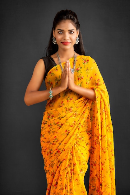 Retrato de uma linda garota indiana em uma pose de saudação para Namaste entrega a mulher indiana em saree tradicional