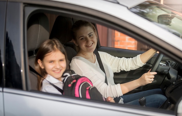 Retrato de uma linda garota indo para a escola com a mãe de carro