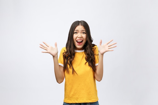 Retrato de uma linda garota jovem e bonita chocada com uma camisa amarela casual