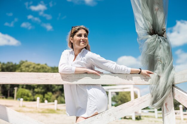 Foto retrato de uma linda garota no gazebo de madeira branco no lago, desfrutar e relaxar na natureza