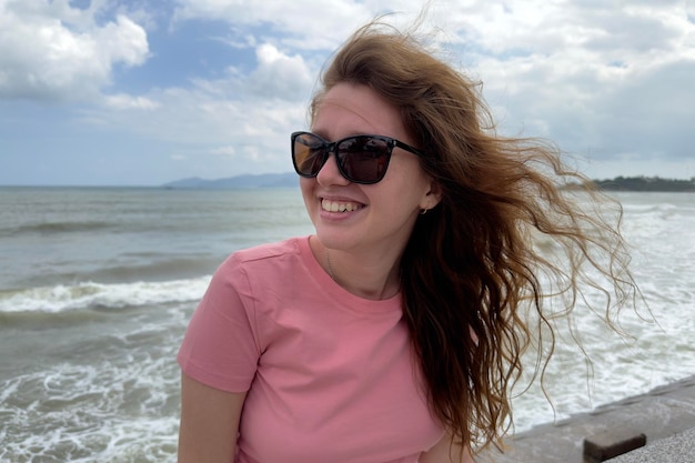 Retrato de uma linda garota positiva e relaxada, uma jovem despreocupada está aproveitando as férias de verão no mar sorrindo olhando para a câmera