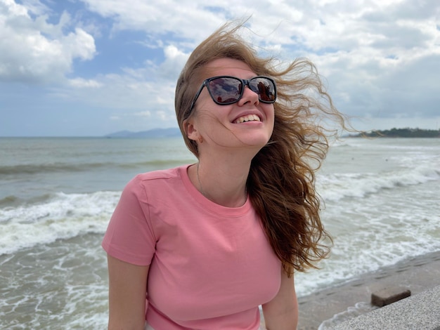 Retrato de uma linda garota positiva e relaxada, uma jovem despreocupada está aproveitando as férias de verão no mar sorrindo olhando para a câmera