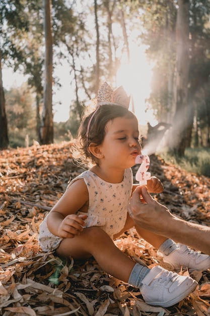 Foto retrato de uma linda garotinha apagando as velas de seu aniversário em uma paisagem de outono