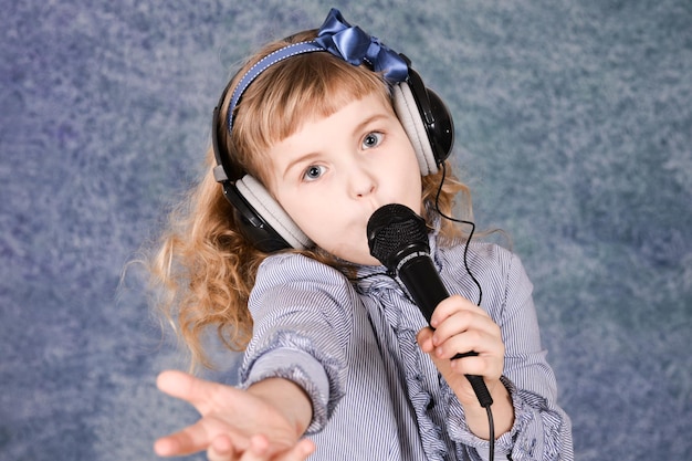 Retrato de uma linda garotinha com microfone em casa cantando