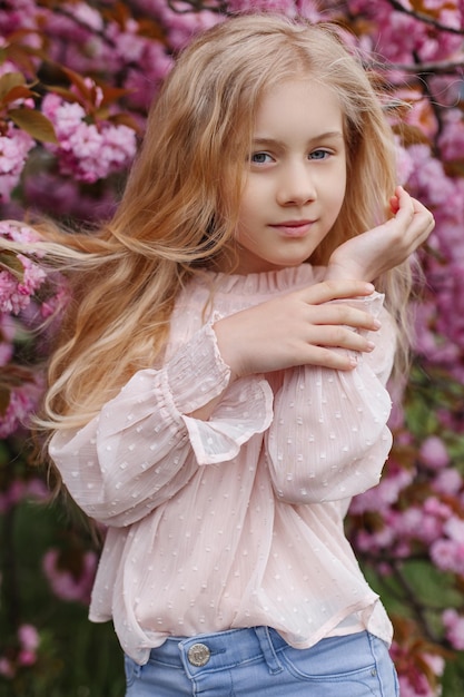 Foto retrato de uma linda garotinha em flores de cerejeira rosa celebração do dia da mulher