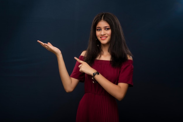Retrato de uma linda jovem apresentando algo mostrando espaço de cópia na palma da mão em um fundo cinza