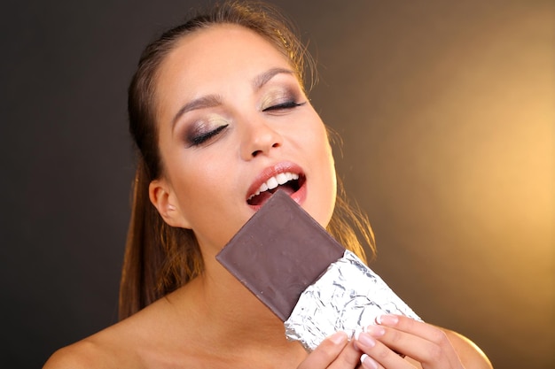 Retrato de uma linda jovem com chocolate em fundo marrom