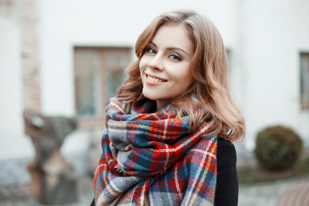 Retrato de uma linda jovem com lindos olhos azuis e um sorriso atraente, com cabelo loiro encaracolado em roupas elegantes de inverno