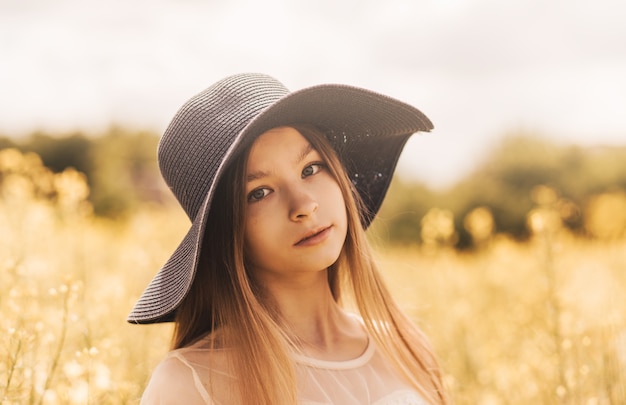 Retrato de uma linda jovem com um chapéu no contexto de um campo de colza.