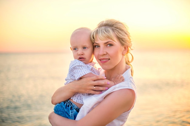 Retrato de uma linda jovem com um filho no fundo de um belo pôr do sol do mar
