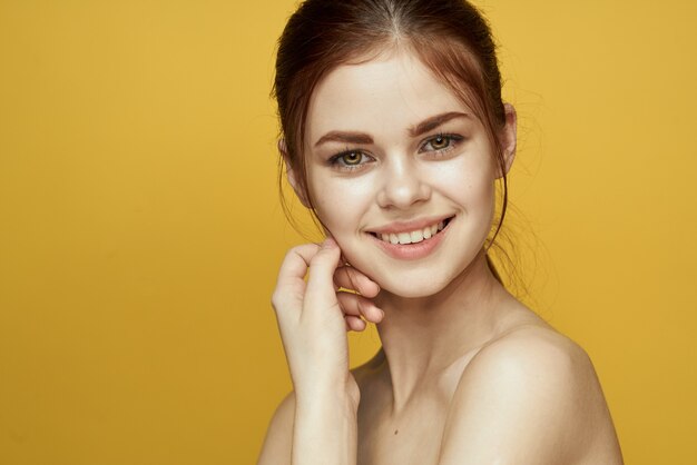 Retrato de uma linda jovem com uma linda pele em um fundo amarelo