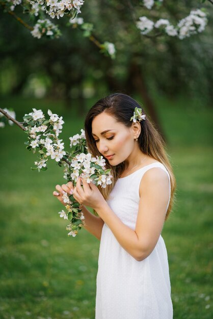 Retrato de uma linda jovem em um pomar de maçã florescendo na primavera