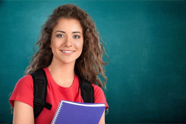 Retrato de uma linda jovem estudante segurando um caderno colorido, isolado no fundo