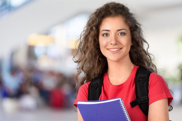 Retrato de uma linda jovem estudante segurando um caderno colorido, isolado no fundo