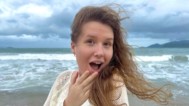 Retrato de uma linda jovem, feliz, alegre, alegre, alegre, aproveitando as férias no mar oceano caminhando na praia de verão em um país tropical sorrindo se divertindo rindo no suéter tricotado