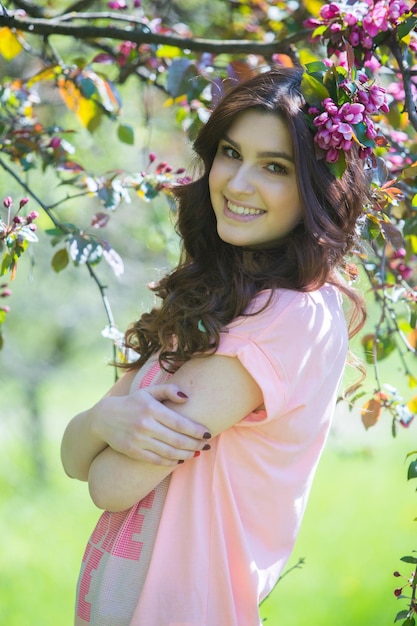 Retrato de uma linda jovem morena de vestido rosa no jardim primavera