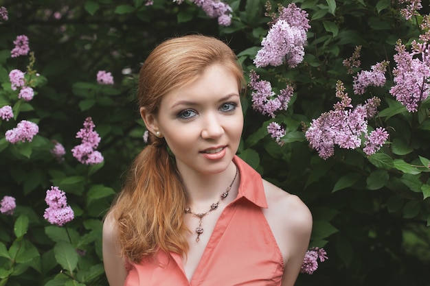 Retrato de uma linda jovem no parque. flores lilás