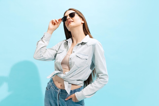 Retrato de uma linda jovem posando com roupa casual isolada sobre o fundo azul do estúdio