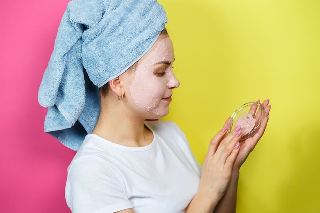 Foto retrato de uma linda jovem que coloca uma máscara refrescante no rosto para rejuvenescer e tonificar a pele. tratamentos de beleza