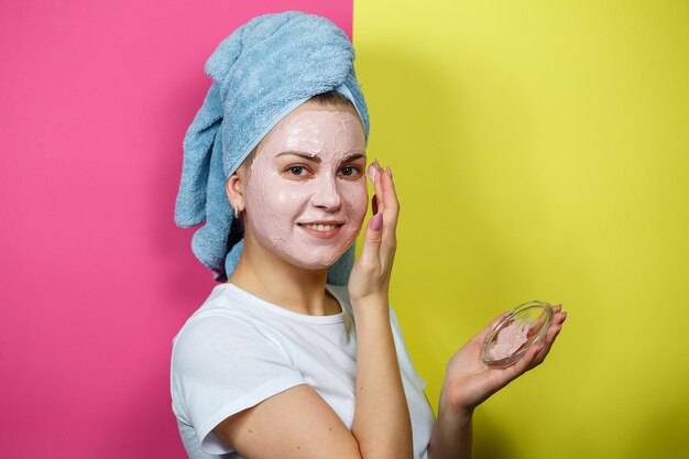 Retrato de uma linda jovem que coloca uma máscara refrescante no rosto para rejuvenescer e tonificar a pele. Tratamentos de beleza