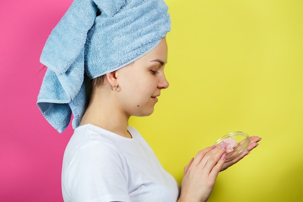 Retrato de uma linda jovem que coloca uma máscara refrescante no rosto para rejuvenescer e tonificar a pele. Tratamentos de beleza