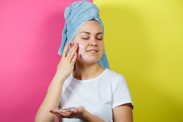 Foto retrato de uma linda jovem que coloca uma máscara refrescante no rosto para rejuvenescer e tonificar a pele. tratamentos de beleza