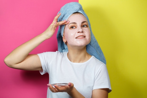 Foto retrato de uma linda jovem que coloca uma máscara refrescante no rosto para rejuvenescer e tonificar a pele. tratamentos de beleza