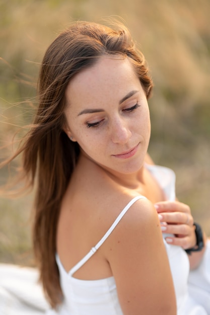 Retrato de uma linda jovem tenra morena em um vestido de verão branco, na natureza.