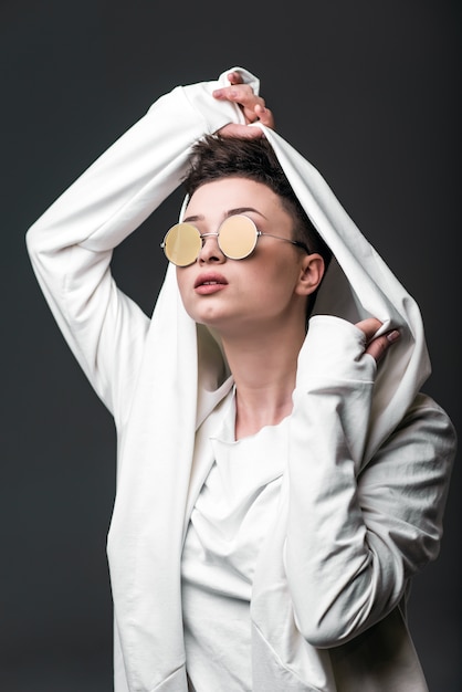 Retrato de uma linda jovem vestindo um casaco branco e óculos de sol